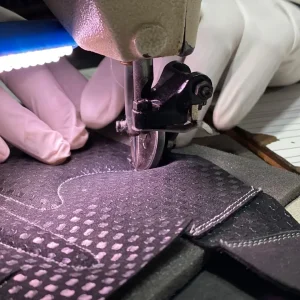 Close-up of an operator stitching a reinforced leather work-glove palm