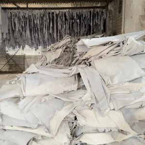 Stacks of processed white leather hides arranged for drying and further work-glove material preparation.