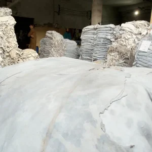Finished white leather hides arranged in labeled batch stacks before glove production.